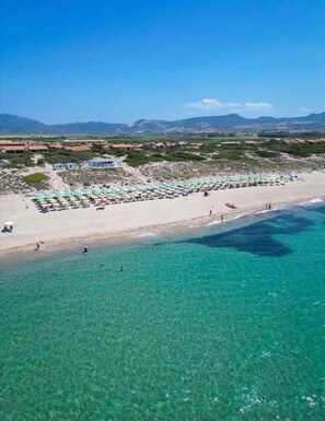 A beach with clear turquoise water, a sandy shore, and a row of beach umbrellas. - Kyma's House - One Bedroom Apartment, Sleeps 4 (Pirotto Li Frati)