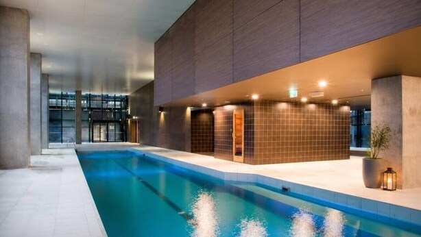 Una piscina interior moderna con agua cristalina, paredes azulejadas e iluminación empotrada.