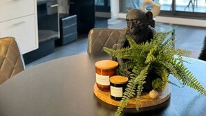 Un comedor moderno con una mesa dispuesta para dos personas, con un centro decorativo que incluye una planta y velas.