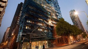 Un edificio de gran altura con fachada de vidrio, rodeado de otros edificios altos.