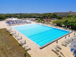 A large rectangular swimming pool with clear blue water, surrounded by lounge chairs and umbrellas. - Villa Aura - Two Bedroom Apartment, Sleeps 6 (Pirotto Li Frati)