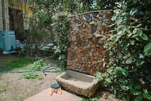 A stone water feature with a small stool nearby, surrounded by greenery. - Villa Aura - Two Bedroom Apartment, Sleeps 6 (Pirotto Li Frati)