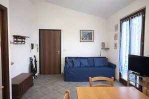 Ein Wohnzimmer mit einem blauen Sofa, einem Holztisch, einem Fernseher und einer Tür.