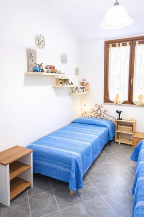 Ein Schlafzimmer mit zwei Betten, einem Holznachttisch, einem Schreibtisch und Regalen mit Dekorationen.