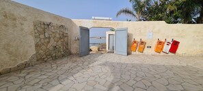 A stone-floored entrance with a stone wall, a door, and a view of the sea.