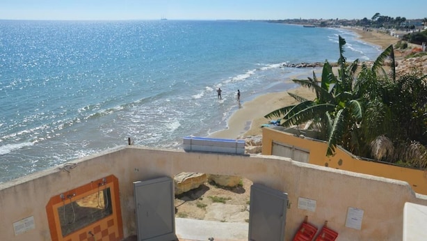 A beach view from a building with a concrete structure, a pool, and a beach in the background. - B&B Mare e Sole Villa Urso (Avola)