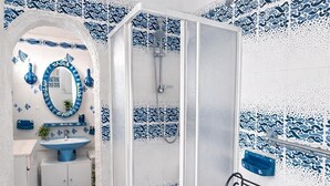 Un baño con ducha, lavamanos y espejo.