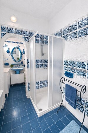 Ein Badezimmer mit Dusche, Waschbecken und Spiegel.