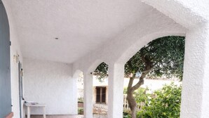 Un espacio al aire libre techado con un banco, un árbol y un camino de piedra.
