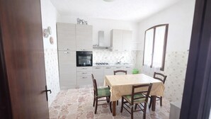 Una cocina compacta con mesa, sillas, estufa y pileta.