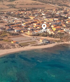 Vue aérienne d’une ville côtière avec ses bâtiments, sa plage et son port de plaisance.
