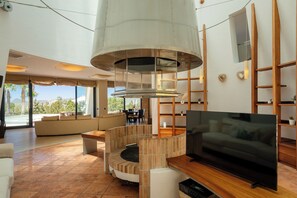 Ein modernes Wohnzimmer mit Fernseher, Kamin und Blick ins Freie.