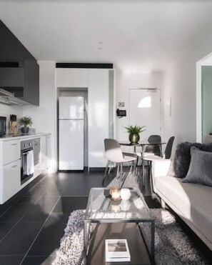 A modern living room with a sofa, coffee table, and dining area. - Melbourne Urban Lookout (Melbourne)
