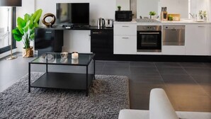 Una sala de estar moderna con una mesa de centro negra, un sofá blanco y un ventanal grande.