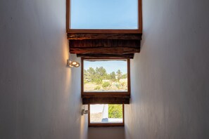 A narrow doorway leading to a room with a small window, a light fixture, and a view of greenery outside. - New! Villa Ses Cases Altes de Arabí (Ibiza)