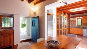 Ein Holztisch mit Stühlen, eine Schüssel und eine Küche mit Holzausbau und einem Kühlschrank.