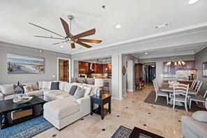 A spacious living room with a sectional sofa, a coffee table, and a ceiling fan.