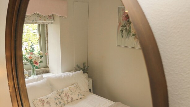 Ein Schlafzimmer mit Bett, Kissen, einem Nachttisch, einem Fenster mit Blick und einem Bild an der Wand.
