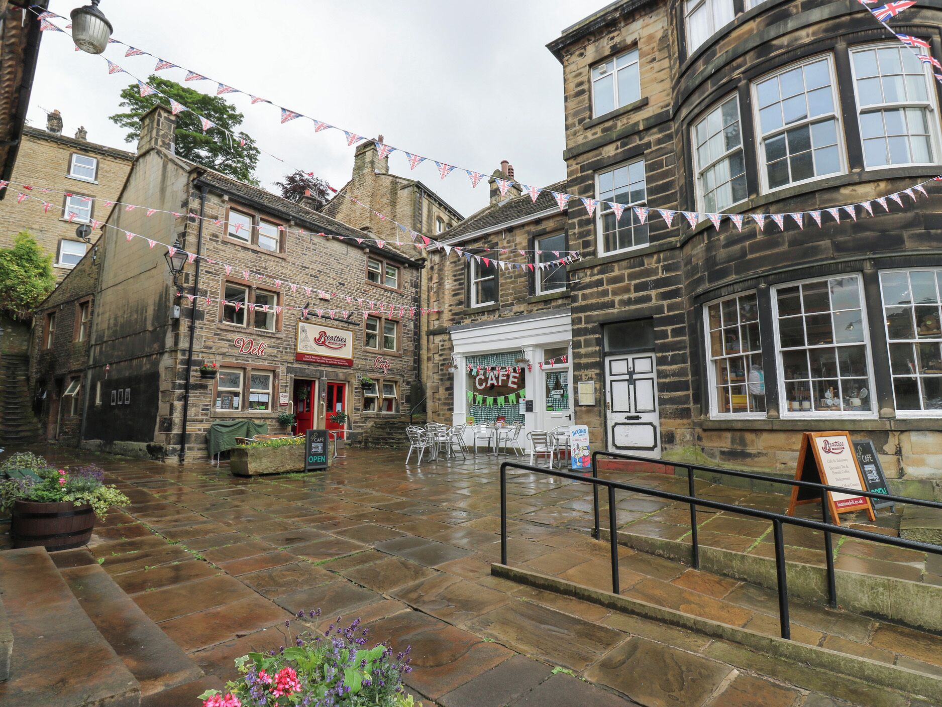 Una calle histórica con edificios de piedra, un café y un pub.
