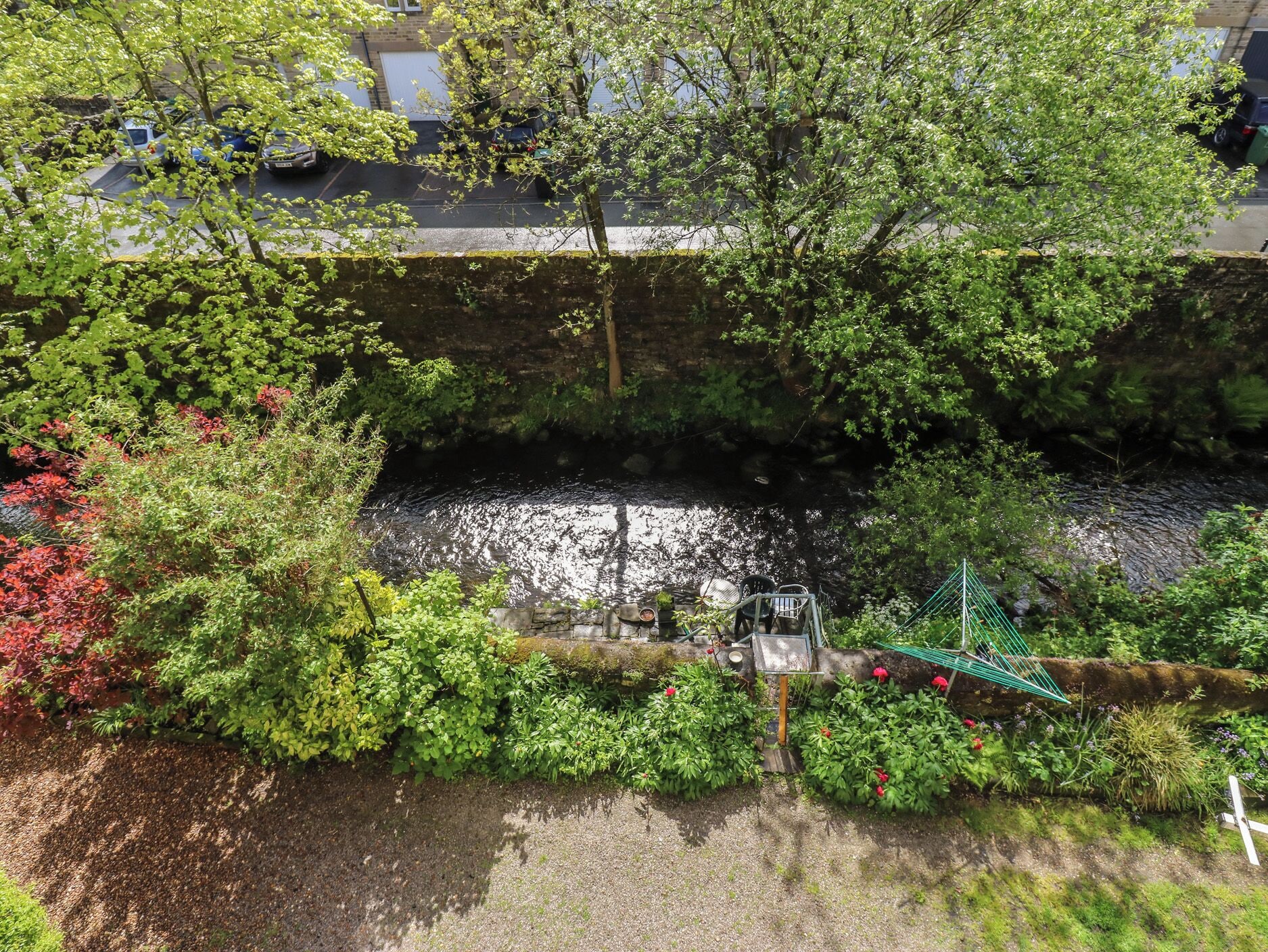 Une rivière traversée par un pont, bordée d’une végétation luxuriante et sur laquelle se trouve une petite cascade.
