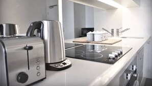 Ett modernt kök med en inbyggd spis, en brödrost och en kaffebryggare.