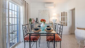 A dining area with a glass table, metal chairs, and a vase with flowers. - Nora Quarteira Apartment T2 (Quarteira)