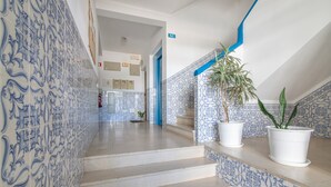 A hallway with blue patterned tiles, a staircase, and potted plants. - Nora Quarteira Apartment T2 (Quarteira)