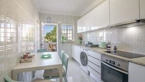 A modern kitchen with a dining area, a washing machine, and a built-in oven. - Nora Quarteira Apartment T2 (Quarteira)