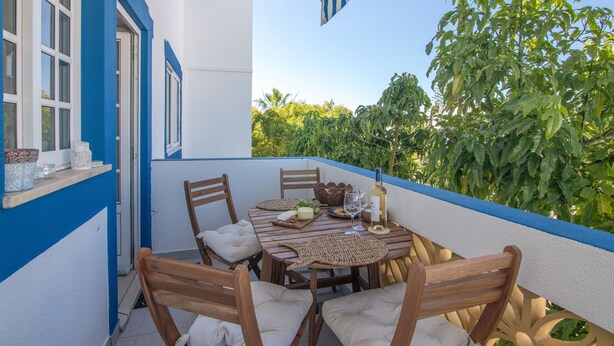 A balcony with a table set for two, chairs, and a bottle of wine. - Nora Quarteira Apartment T2 (Quarteira)