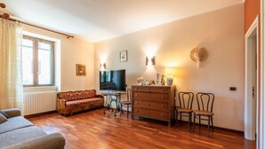 A living room with a sofa, TV, wooden floor, and a dresser. - GuestHost - Comfy Apartment near the sea (Bisceglie)