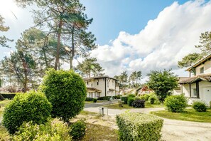 Et boligområde med huse, velplejet græsplæne og klar himmel.