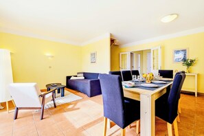 Un coin repas avec une table dressée pour quatre personnes, un canapé et un fauteuil.