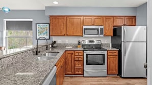 A kitchen with granite countertops, wooden cabinets, stainless steel appliances, and a window with a view. - Cozy 2 Bed 2 Bath Condo! Gated Waterway Community in Myrtle Beach (Myrtle Beach)