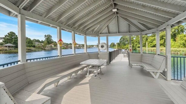 A covered deck with benches and tables, overlooking a body of water. - Cozy 2 Bed 2 Bath Condo! Gated Waterway Community in Myrtle Beach (Myrtle Beach)