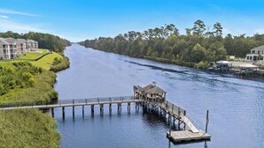 A river with a wooden dock and a gazebo, surrounded by greenery and buildings. - Cozy 2 Bed 2 Bath Condo! Gated Waterway Community in Myrtle Beach (Myrtle Beach)