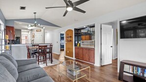 A modern living room with a sofa, coffee table, and a TV stand. There is a dining area with chairs and a kitchen visible in the background. - Cozy 2 Bed 2 Bath Condo! Gated Waterway Community in Myrtle Beach (Myrtle Beach)