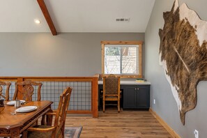 Un coin repas avec une table et des chaises en bois, une cuisine avec des meubles sombres et un grand mur recouvert de fourrure.