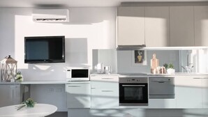 A modern kitchen with a flat-screen TV, built-in oven, and microwave. - Prime Melbourne CBD View Apartment (Melbourne)