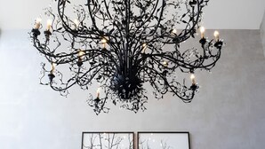 A chandelier, a wall-mounted picture, a black console table, and two patterned chairs. - Llawnroc Hotel (Gorran Haven)