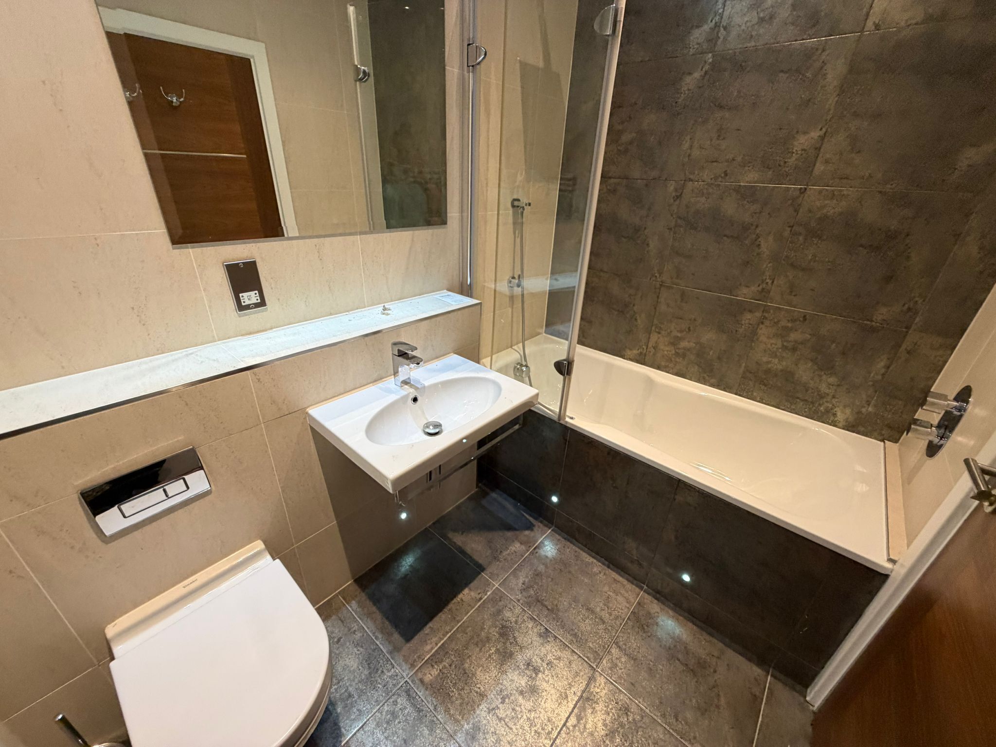 A bathroom with a white sink, a toilet, a shower, and a mirror.