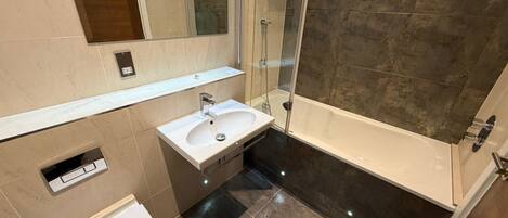 A bathroom with a white sink, a toilet, a shower, and a mirror.