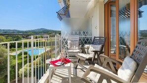 A balcony with a pool, white cushioned chairs, and a table with a red tray. - Roseraie Apartment with Private Pool, Wi-Fi, and Air Conditioning (Antibes)