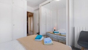 A bedroom with a bed, two towels, a chair, a bedside table, and a wardrobe. - Roseraie Apartment with Private Pool, Wi-Fi, and Air Conditioning (Antibes)