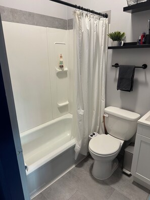 A bathroom with a bathtub, toilet, and shower curtain.