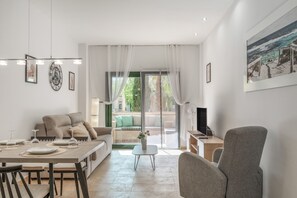 Una sala de estar moderna con comedor, un sofá, un televisor y vistas a un balcón.