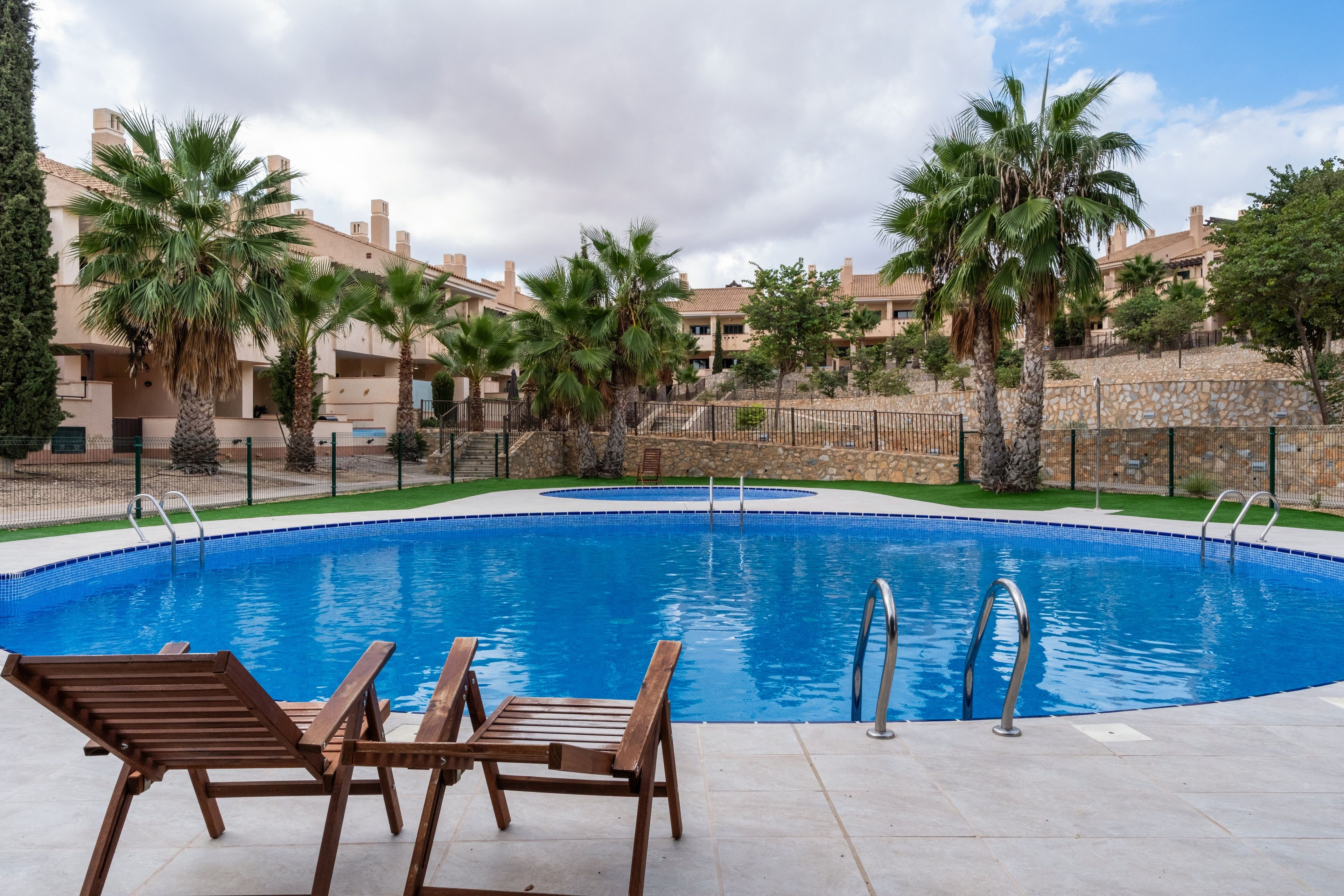 A swimming pool with lounge chairs and palm trees.