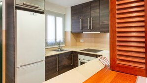 Eine Küche mit dunklen Holzschränken, einem weißen Kühlschrank, einer Spüle und einer Holzarbeitsplatte.