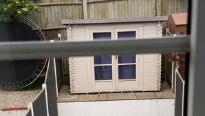 A fenced backyard with artificial grass, a small shed, and a wooden fence. - 2 Bedroom With Electric Charging and Parking (Gillingham)