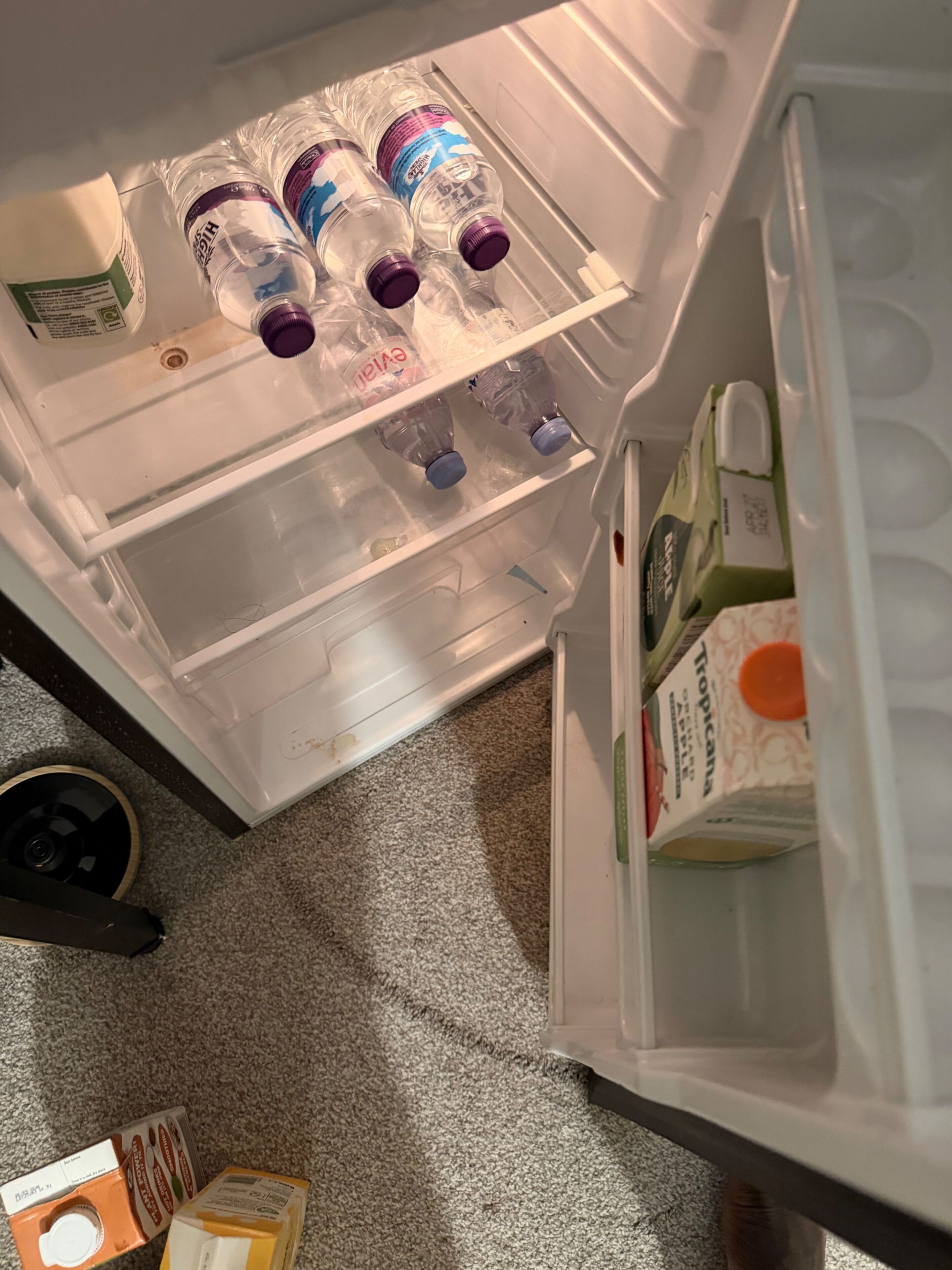 An open refrigerator with bottles, a carton of milk, and a carton of orange juice.