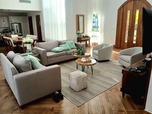 Ein modernes Wohnzimmer mit einer Couch, Sesseln, einem Couchtisch und einem Fernseher.